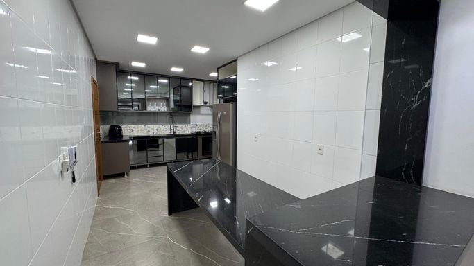 Cozinha americana totalmente planejada com geladeira de duas portas.