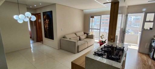 Sala de dois ambientes com um sofá, painel de TV e sacada gourmet.