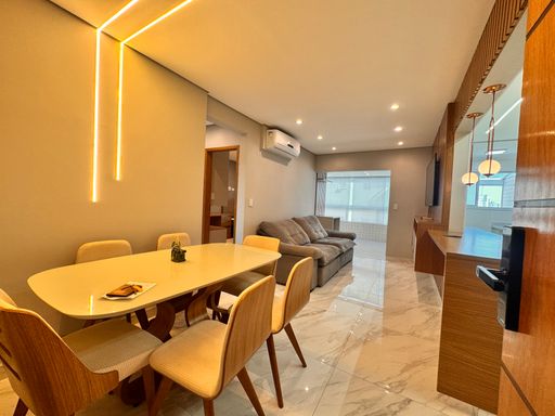 Sala de dois ambientes, com ar condicionado, sofá, mesa de jantar para seis pessoas, iluminação em LED e piso em porcelanato.