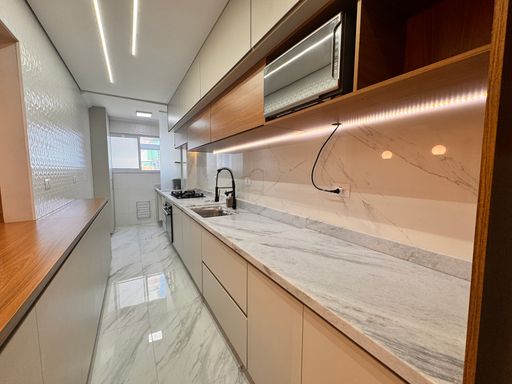 Cozinha americana iluminada, com armários planejados e iluminação em LED.