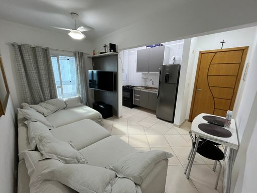 Sala com um sofá cinza, ventilador de teto e sacada.