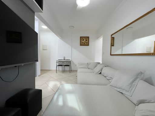 Sala com um sofá cinza, ventilador de teto e sacada.