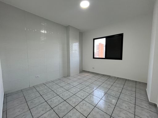 Dormitório espaçoso e bem iluminado com paredes brancas.