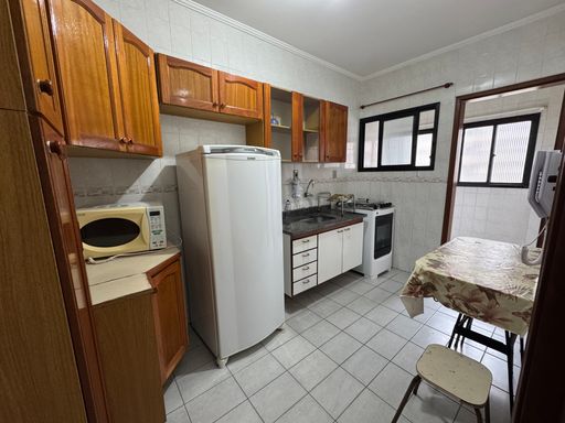 Cozinha com armários, geladeira, pia, fogão e mesa.