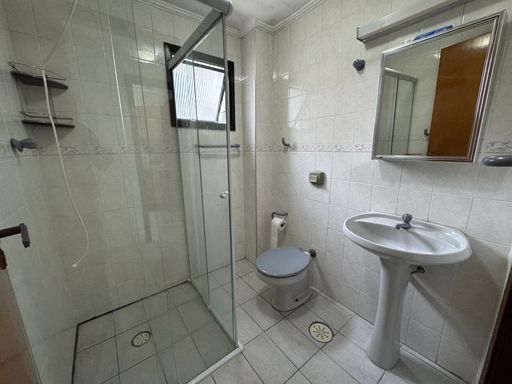 WC social com uma pia branca e box de vidro.