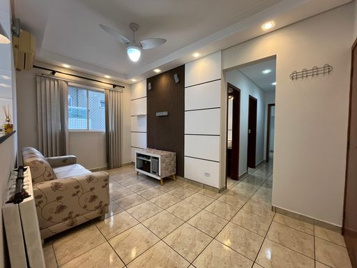 Sala com muita iluminação natural, sofá, ventilador de teto e ar-condicionado.