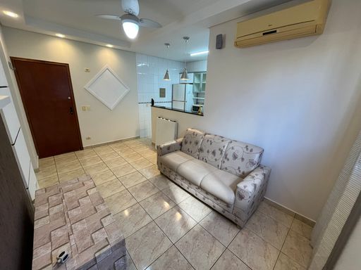 Sala com muita iluminação natural, sofá, ventilador de teto e ar-condicionado.