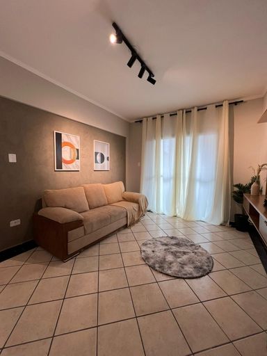 Sala ampla e bem iluminada com um sofá e painel de TV.