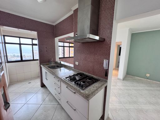 Cozinha americana com armários planejados e uma geladeira.