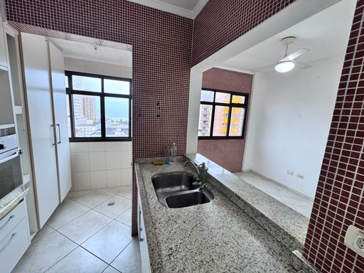 Cozinha americana com armários planejados e uma geladeira.