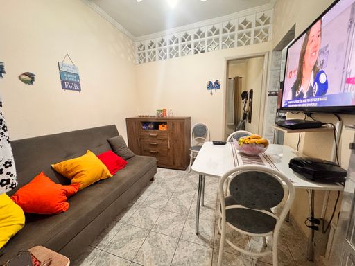 Sala com sofá cama, mesa e TV.