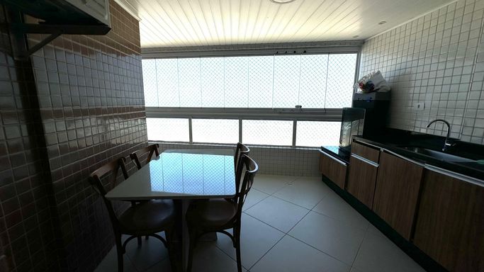 Sacada gourmet envidraçada com vista para o mar.