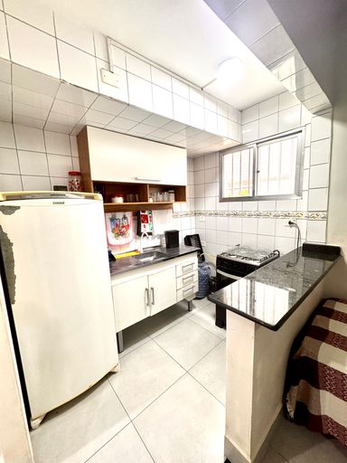 Sala living com uma cama de casal, beliche e uma cama de solteiro e ventilador de teto.