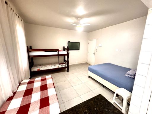 Sala living com uma cama de casal, beliche e uma cama de solteiro e ventilador de teto.