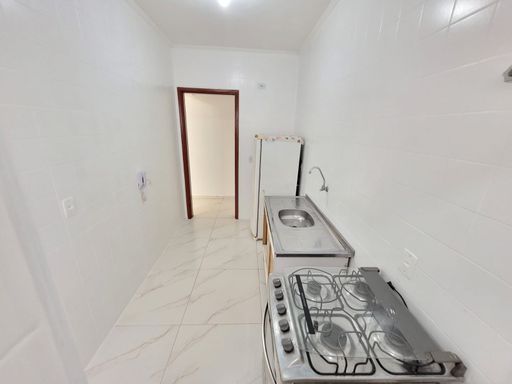 Cozinha com pia, gabinete, fogão, geladeira e piso em porcelanato.
