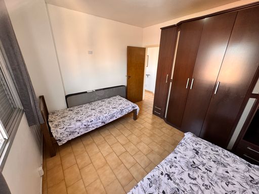 Dormitório muito bem iluminado com duas camas de solteiro e uma guarda-roupa.