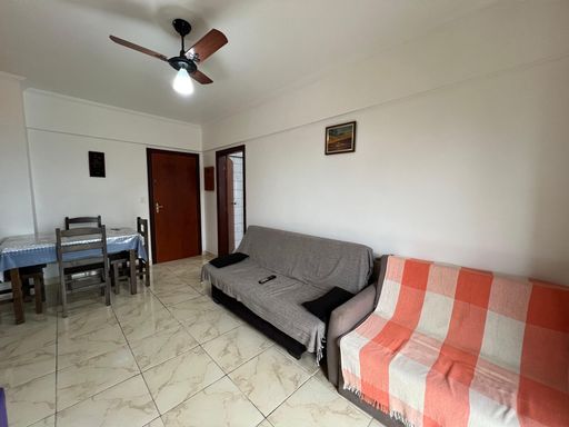 Sala ampla e bem iluminada com uma parede amarela, ventilador de teto e sacada.
