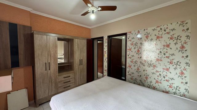 Suíte com uma cama de casal, guarda-roupa e ventilador de teto.