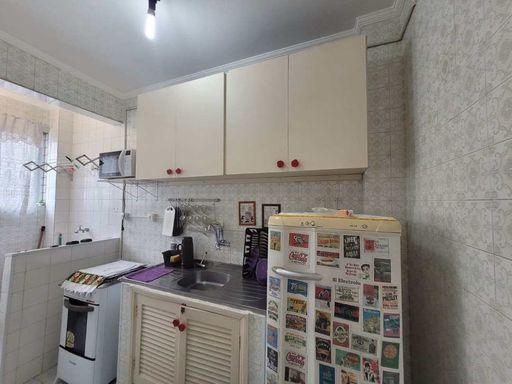 Cozinha com uma geladeira, fogão e armários brancos.