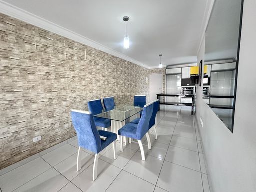 Sala com dois ambientes, equipada com sofá, painel para TV, mesa de jantar para seis pessoas e espelho de parede.