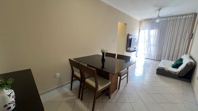 Sala de 2 ambientes com sofá, painel de TV e mesa de jantar.