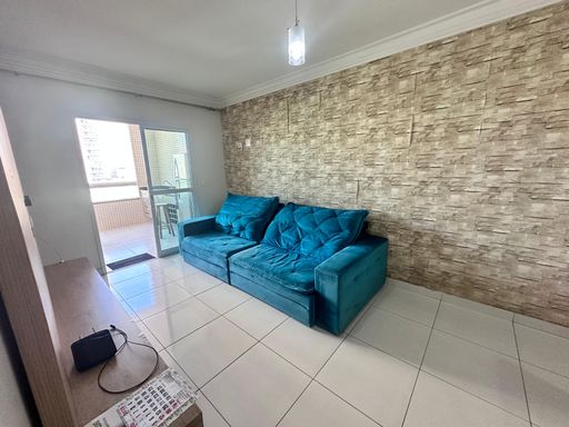 Sala com dois ambientes, equipada com sofá, painel de TV, mesa de jantar para seis pessoas e espelho de parede.
