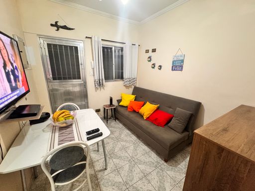 Sala com sofá cama, mesa e TV.