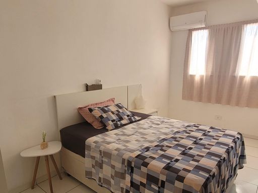 Suíte com cama de casal, criado mudo e ar-condicionado.