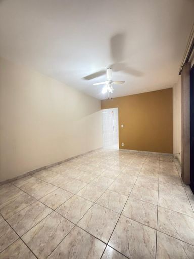 Sala espaçosa com um ventilador de teto e sacada.