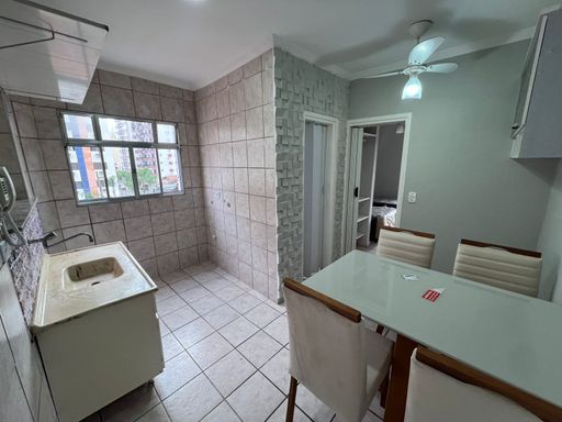 Cozinha americana com pia, gabinete, janela ampla que proporciona boa iluminação e mesa de 4 lugares e ventilador de teto.