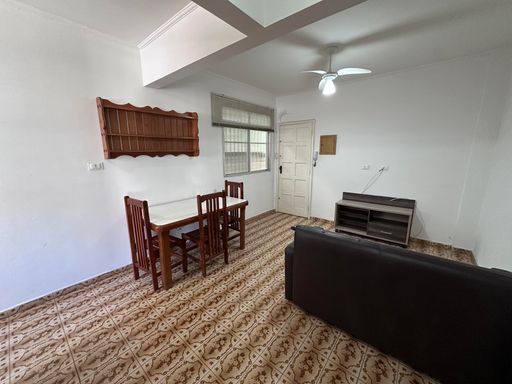 Sala ampla e bem iluminada com um ventilador de teto, sofá e mesa de jantar.