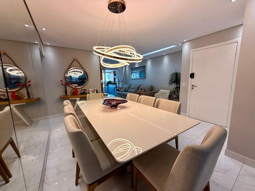 Sala ampla de 2 ambientes com uma parede espelhada e  mesa de jantar.