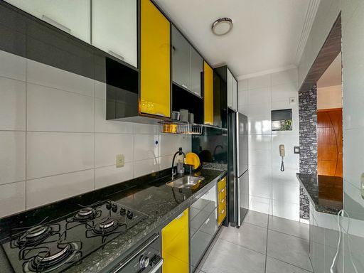Cozinha americana com armários planejados com fogão embutido e geladeira.