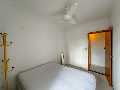 Dormitório com 1 cama de casal, ventilador de teto e acesso à sacada gourmet.