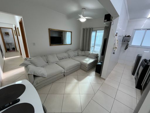 Sala com um sofá cinza, ventilador de teto e sacada.