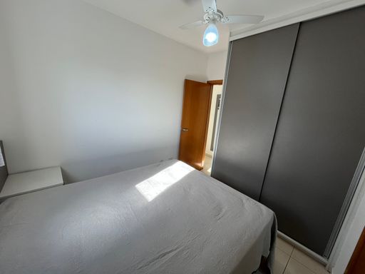 Suíte planejada com uma cama de casal e ventilador de teto.