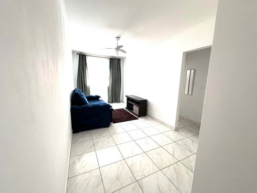 Sala bem iluminada com um sofá azul e ventilador de teto.