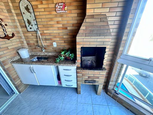 Sacada gourmet envidraçada com vista para o mar.