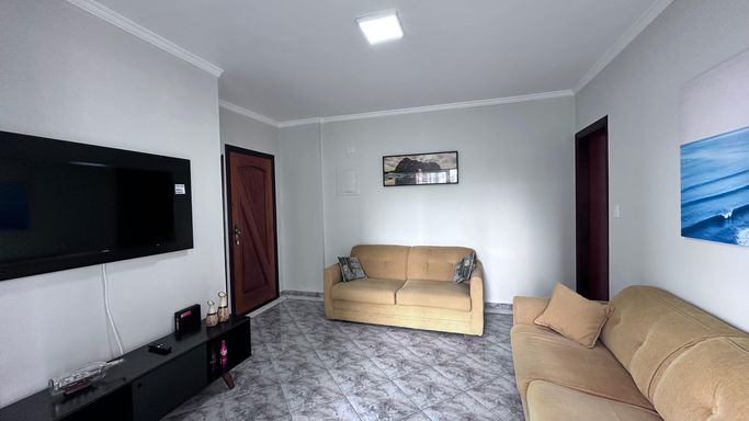 Sala bem iluminada com 2 sofás, espelho e acesso a sacada.