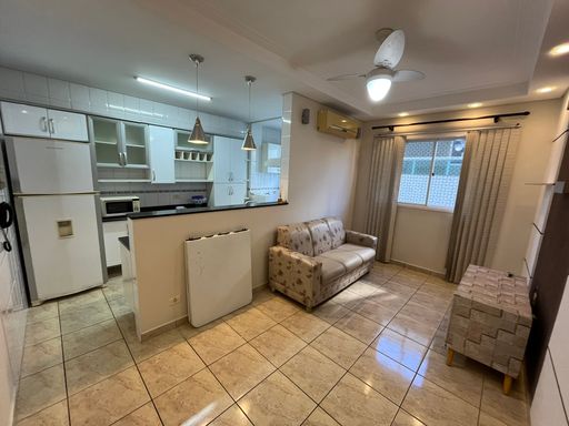 Sala com muita iluminação natural, sofá, ventilador de teto e ar-condicionado.