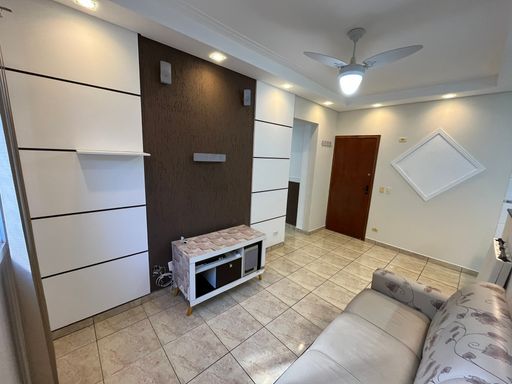 Sala com muita iluminação natural, sofá, ventilador de teto e ar-condicionado.