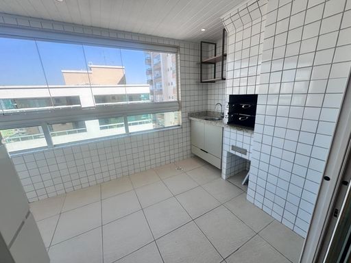 Sacada gourmet envidraçada com churrasqueira a carvão e vista livre.