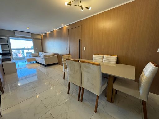 Sala de dois ambientes com nichos na parede, ar-condicionado, sofá e acesso à sacada gourmet.