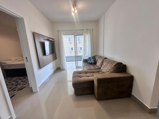 Sala ampla de 2 ambientes com um sofá e acesso a sacada gourmet.