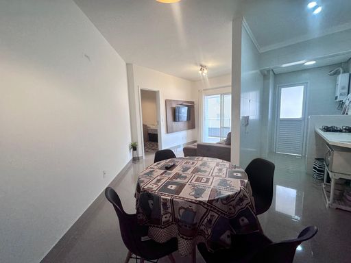 Sala ampla de 2 ambientes com um sofá e acesso a sacada gourmet.