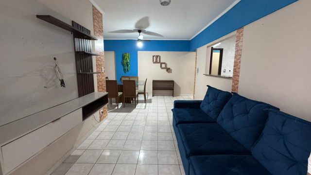 Sala de 2 ambientes com um sofá, mesa de jantar, painel de TV, ventilador de teto.