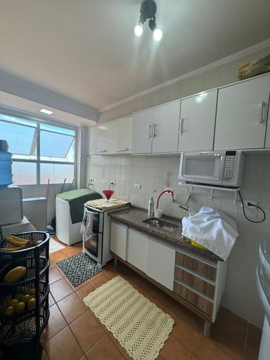 Cozinha com pia, gabinete e armários brancos.