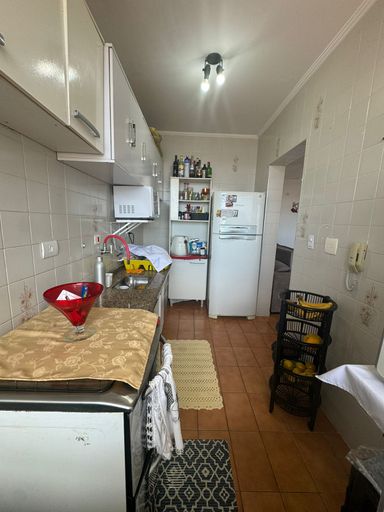 Cozinha com pia, gabinete e armários brancos.