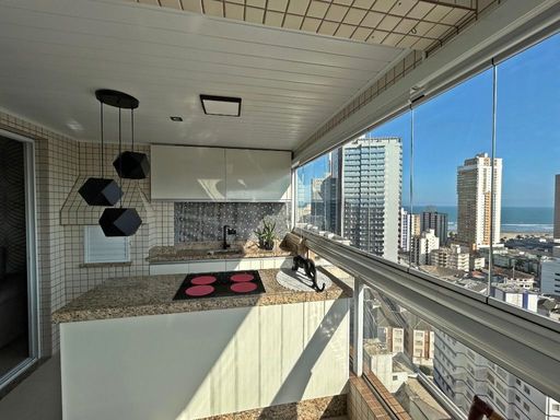 Sacada gourmet envidraçada com vista para o mar.