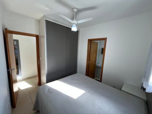 Suíte planejada com uma cama de casal e ventilador de teto.